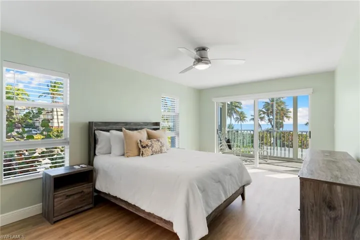 Primary Bedroom featuring access to outside, wood finished floors, and a ceiling fan