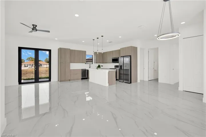 Kitchen with modern cabinets, a kitchen island, pendant lighting, open floor plan, and stainless steel appliances