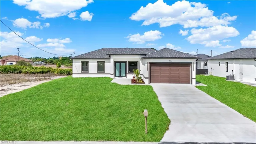 Prairie-style home with a front yard, stucco siding, a garage, french doors, and concrete driveway