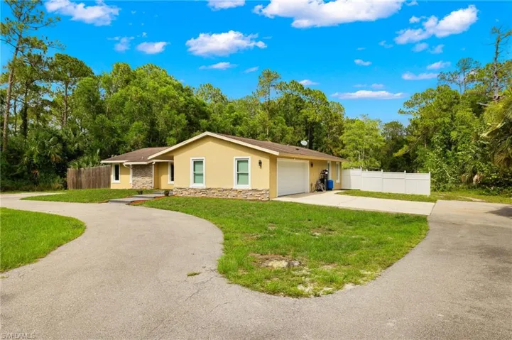 Single story home with stucco siding, stone siding, curved driveway, and a garage
