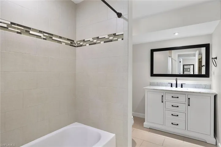 Bathroom featuring light tile patterned floors, vanity, and shower / tub combination