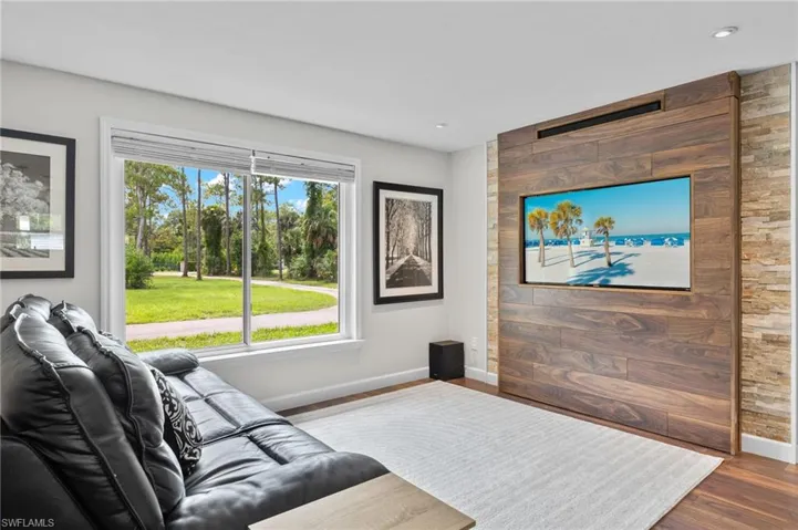 Living room with dark wood finished floors and an accent wall