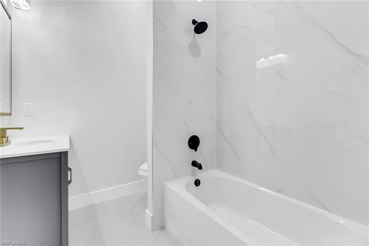 Full bathroom with toilet, vanity, and tiled shower / bath combo