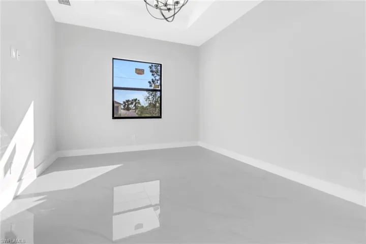 Empty room with a raised ceiling and a chandelier