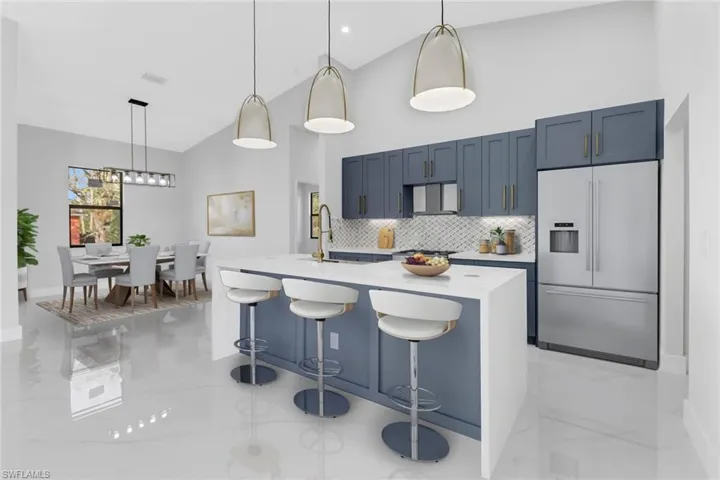 Kitchen with built in refrigerator, tasteful backsplash, a kitchen island with sink, a kitchen breakfast bar, and hanging light fixtures