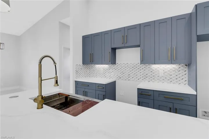 Kitchen featuring lofted ceiling, backsplash, and sink