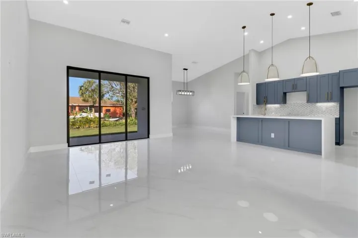 Kitchen featuring lofted ceiling, blue cabinetry, pendant lighting, and backsplash