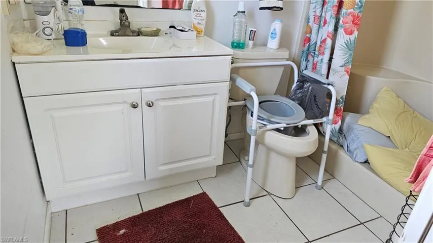 Full bath with vanity, light tile patterned floors, and a shower with shower curtain