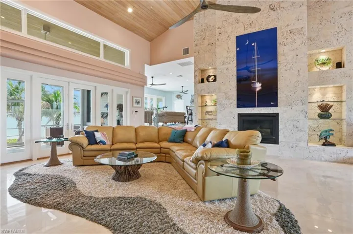 Living room with a vaulted wooden ceiling, a premium fireplace, recessed lighting, built in shelves, and a ceiling fan