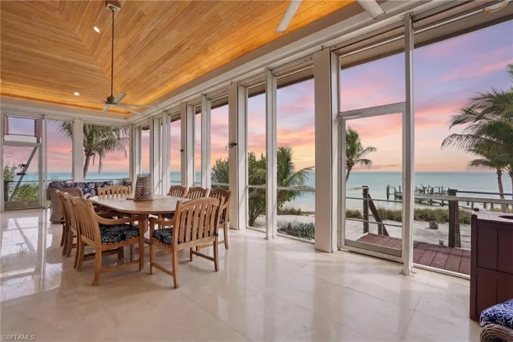 Sunroom / solarium with wooden ceiling, a water view, and expansive windows