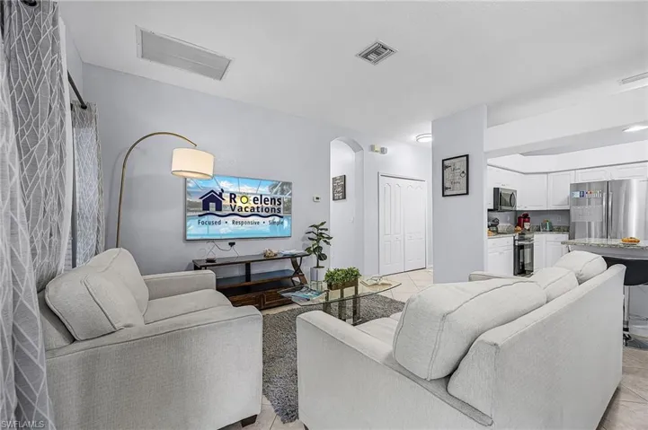Living room featuring arched walkways and light tile patterned flooring