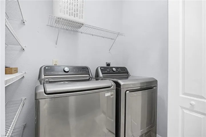 Laundry room featuring a textured wall and washing machine and dryer