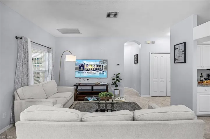 Living area with arched walkways and light tile patterned floors