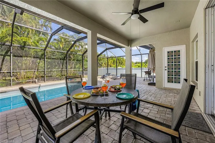 Sunroom / solarium with a patio, a ceiling fan, and outdoor dining space