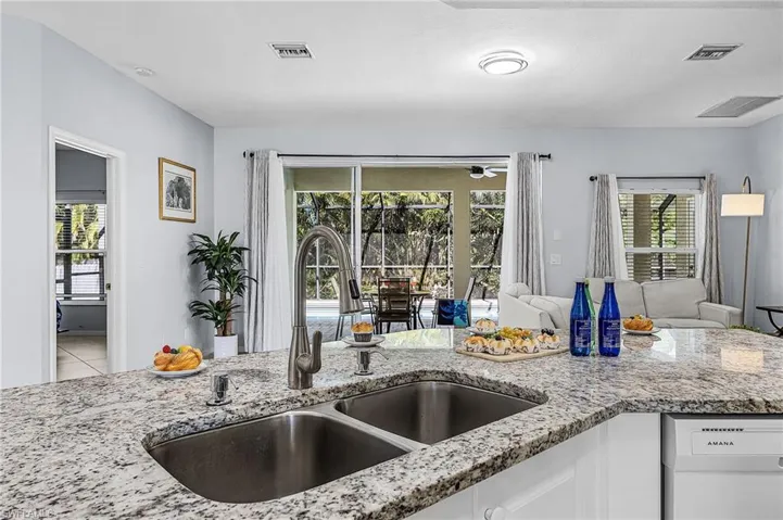 Kitchen featuring light stone counters, white dishwasher, white cabinets, and open floor plan