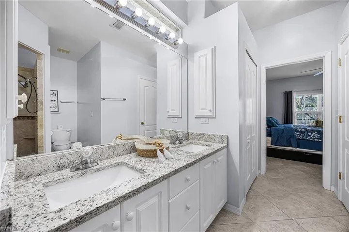 Ensuite bathroom with double vanity, a tile shower, and light tile patterned floors