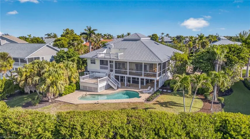 Back of house featuring a sunroom, stairway, a lawn, an outdoor pool, and a patio