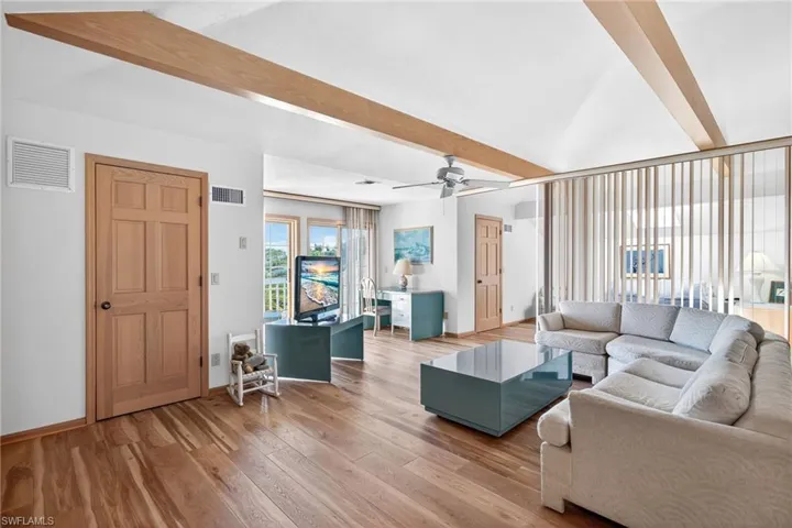 Loft with beam ceiling, light wood-style flooring, and a ceiling fan