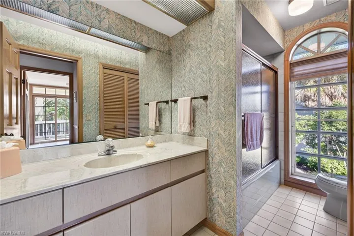 Full bathroom featuring wallpapered walls, plenty of natural light, vanity, a stall shower, and light tile patterned floors