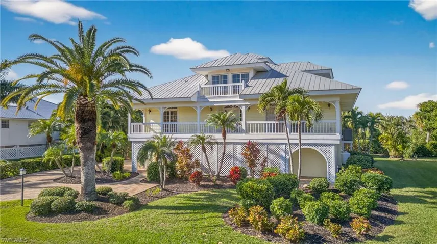 Raised beach house featuring a front lawn, a balcony, and a metal roof