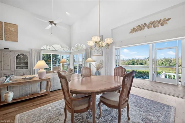 Dining area with wood-type flooring, high vaulted ceiling, a chandelier, and a ceiling fan