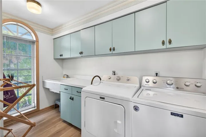 Laundry room featuring crown molding, washing machine and dryer, light wood finished floors, and cabinet space
