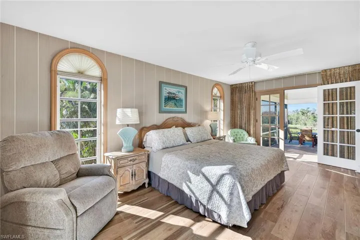 Bedroom with wood-type flooring, multiple windows, and ceiling fan