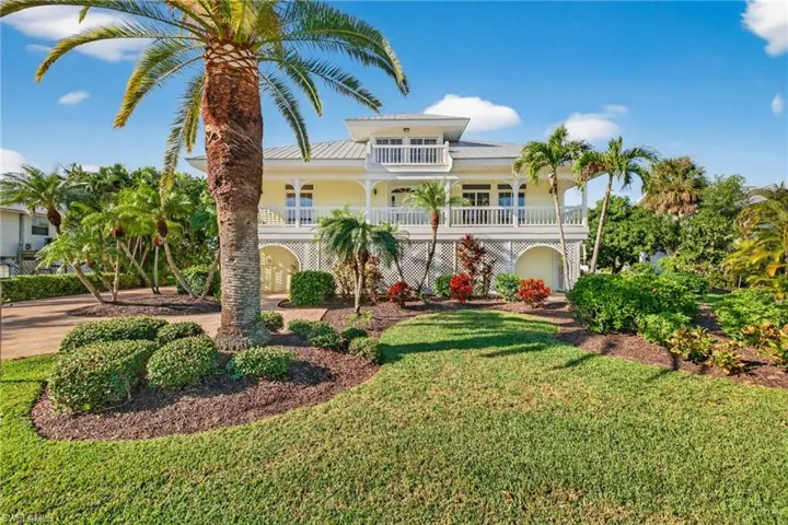 Coastal inspired home with a metal roof, a balcony, and a front yard