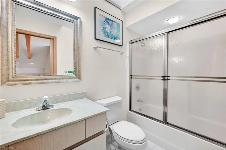 Bathroom with bath / shower combo with glass door and vanity