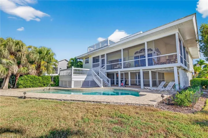 Back of property featuring an outdoor pool, a patio, and a yard