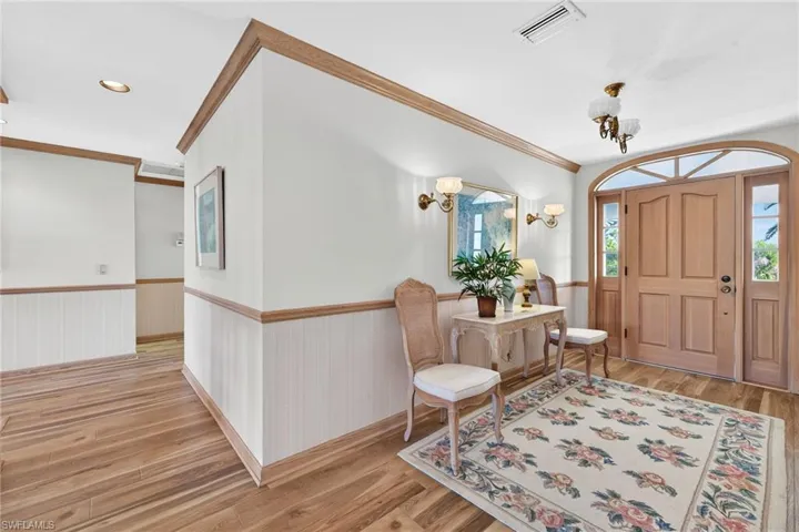 Foyer featuring a wainscoted wall, light wood-style floors, and crown molding