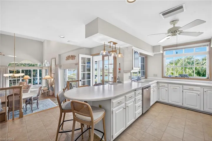 Kitchen with a ceiling fan, a peninsula, a breakfast bar, white cabinetry, and light countertops