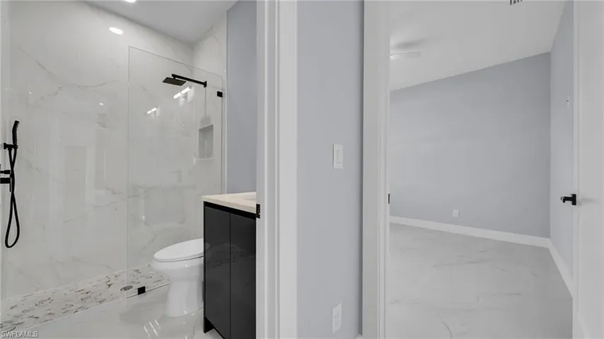 Bathroom featuring marble tiled flooring, a marble finish shower, vanity, and recessed lighting