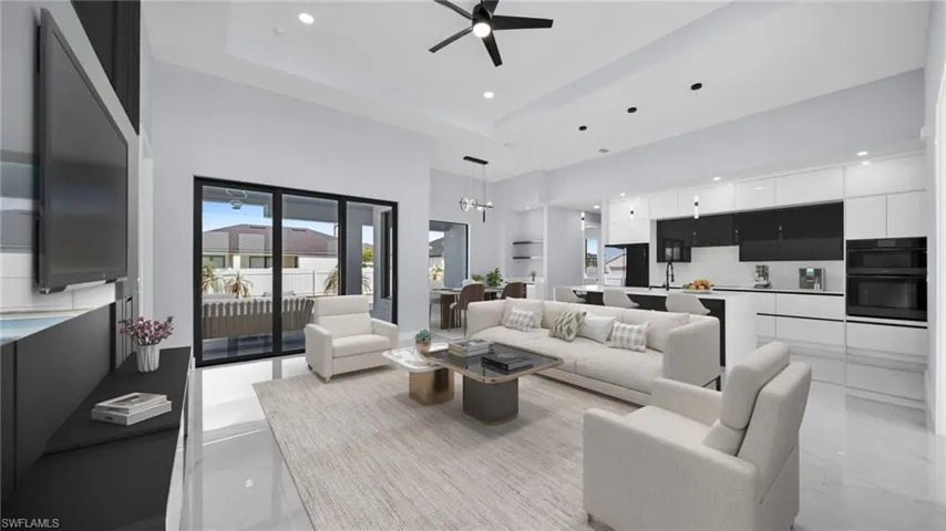 Living room featuring a high ceiling, recessed lighting, a ceiling fan, a tray ceiling, and a chandelier
