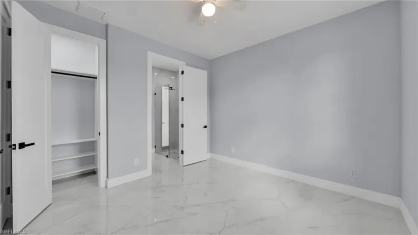 Unfurnished bedroom with light marble finish floors, a closet, and ceiling fan