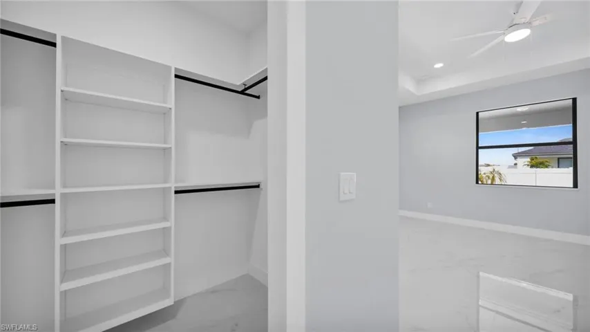 Spacious closet featuring light marble finish flooring and a ceiling fan