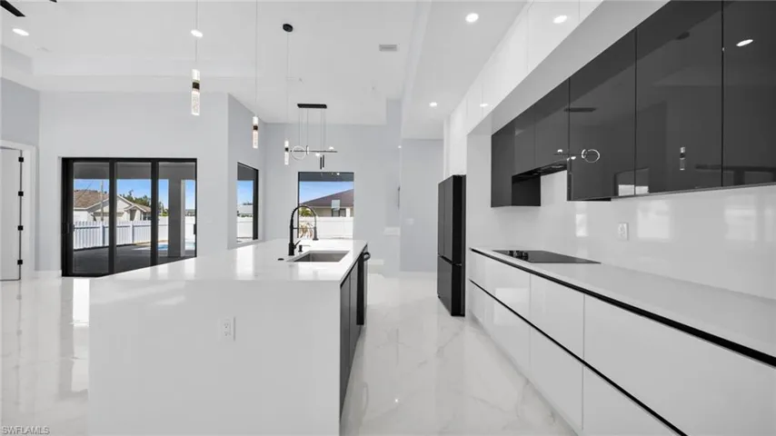 Kitchen with decorative light fixtures, dark cabinets, modern cabinets, light marble finish floors, and recessed lighting