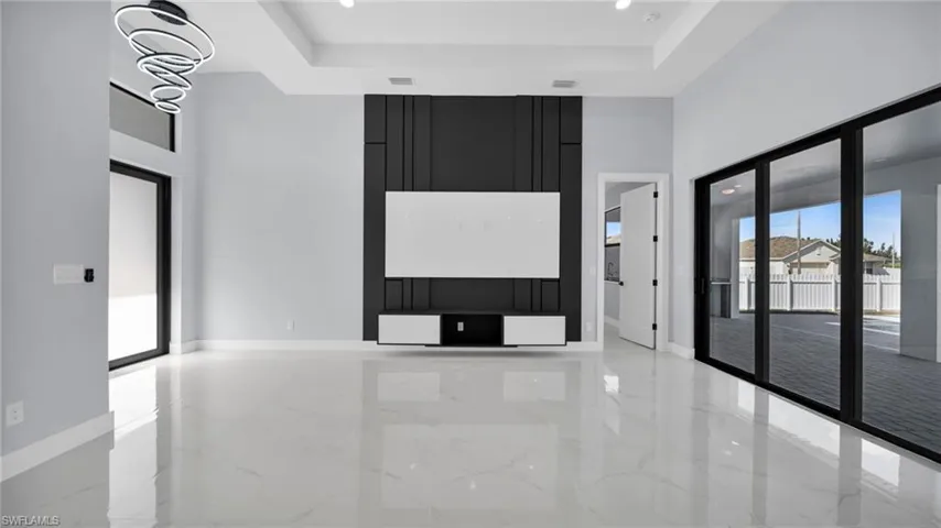 Spare room featuring a high ceiling, light marble finish floors, recessed lighting, and a raised ceiling