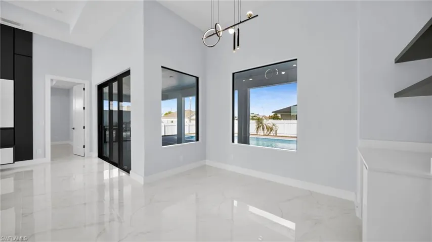 Unfurnished dining area with light marble finish flooring, a high ceiling, and a chandelier