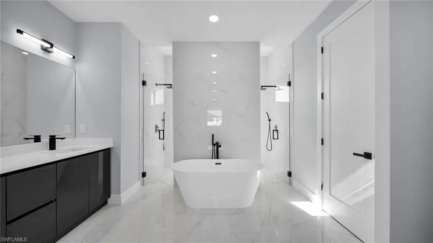 Full bathroom with a freestanding tub, a marble finish shower, recessed lighting, light marble finish flooring, and vanity