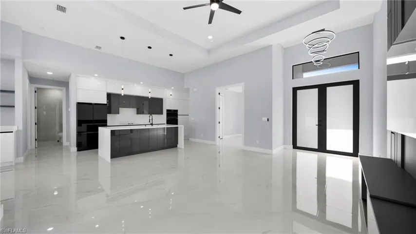 Kitchen featuring modern cabinets, white cabinets, a high ceiling, open floor plan, and pendant lighting