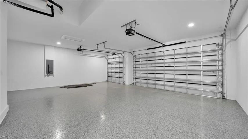 Garage with recessed lighting, electric panel, and a garage door opener