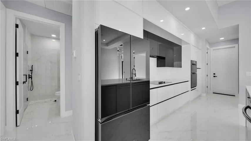 Bathroom featuring vanity, light marble finish flooring, a marble finish shower, and recessed lighting