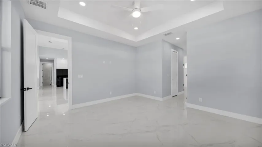 Spare room featuring recessed lighting, a tray ceiling, light marble finish floors, and ceiling fan