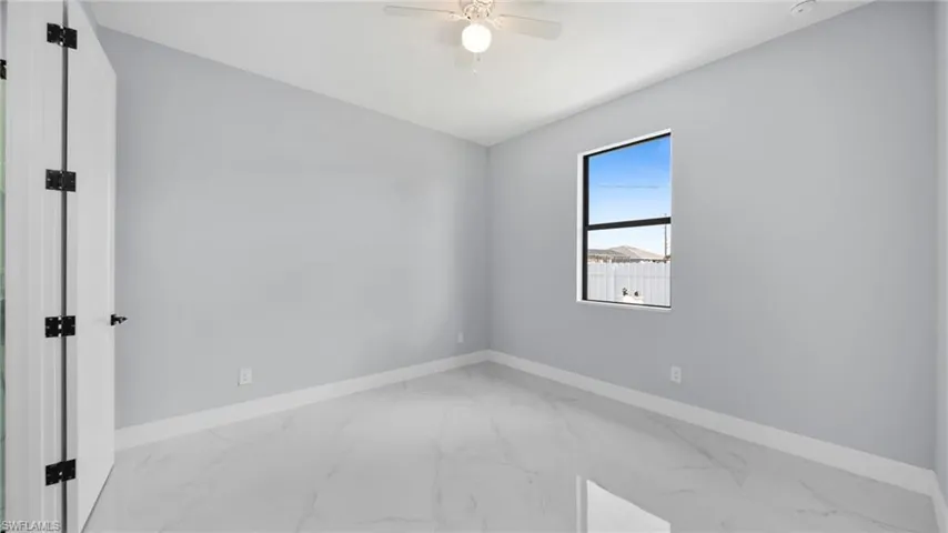 Empty room featuring marble look tile flooring and baseboards