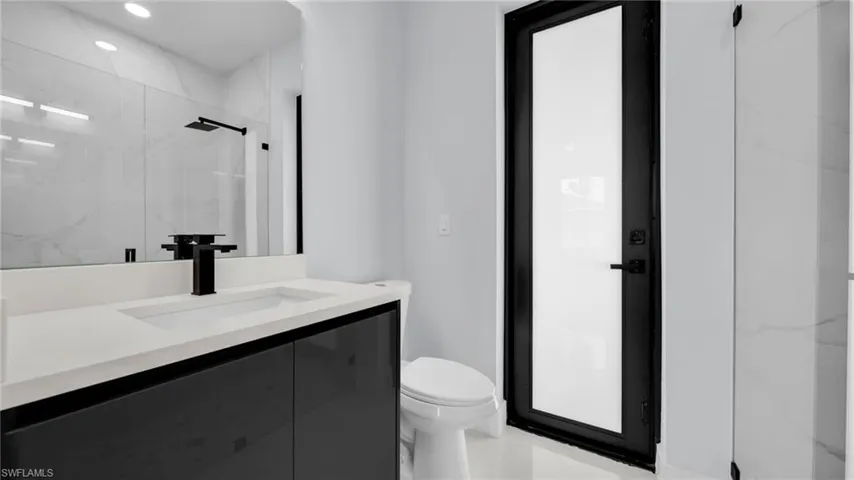 Bathroom featuring vanity, a marble finish shower, and recessed lighting