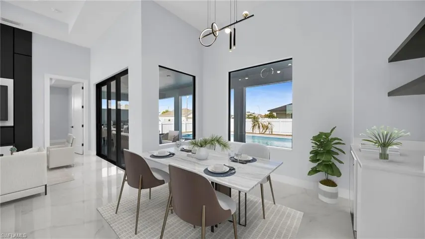 Dining space with light marble finish floors, a towering ceiling, and a chandelier