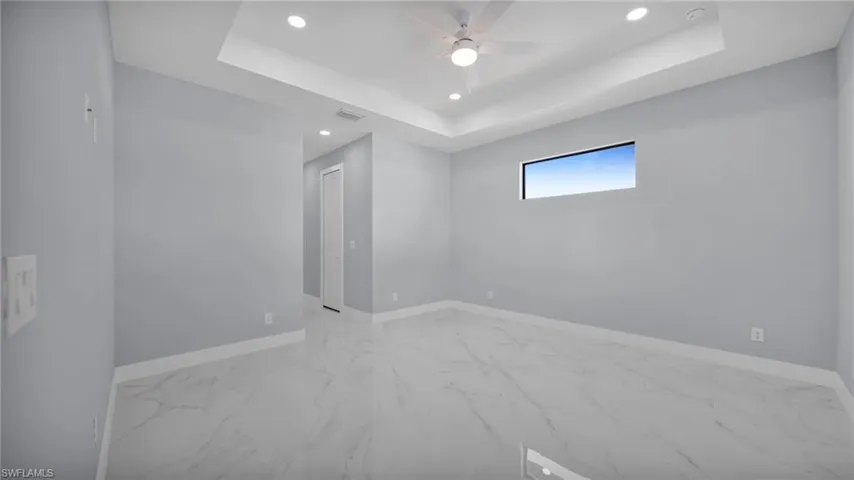 Unfurnished room with light marble finish floors, a raised ceiling, recessed lighting, and ceiling fan
