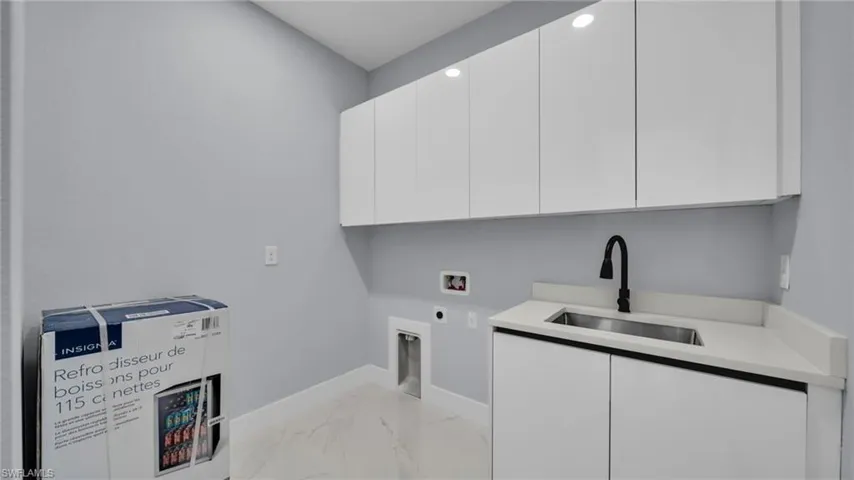 Laundry area with light marble finish flooring, washer hookup, cabinet space, and hookup for an electric dryer