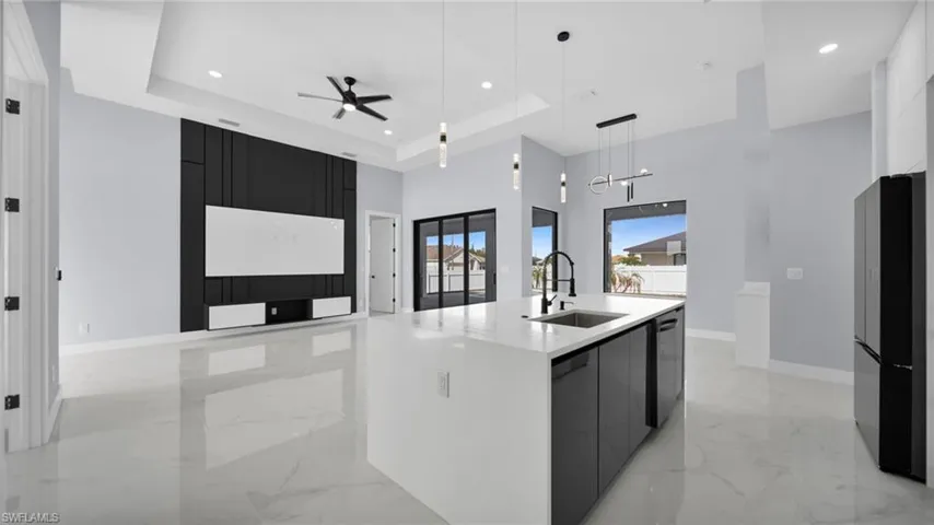 Kitchen with pendant lighting, dark cabinets, light marble finish flooring, ceiling fan, and a towering ceiling